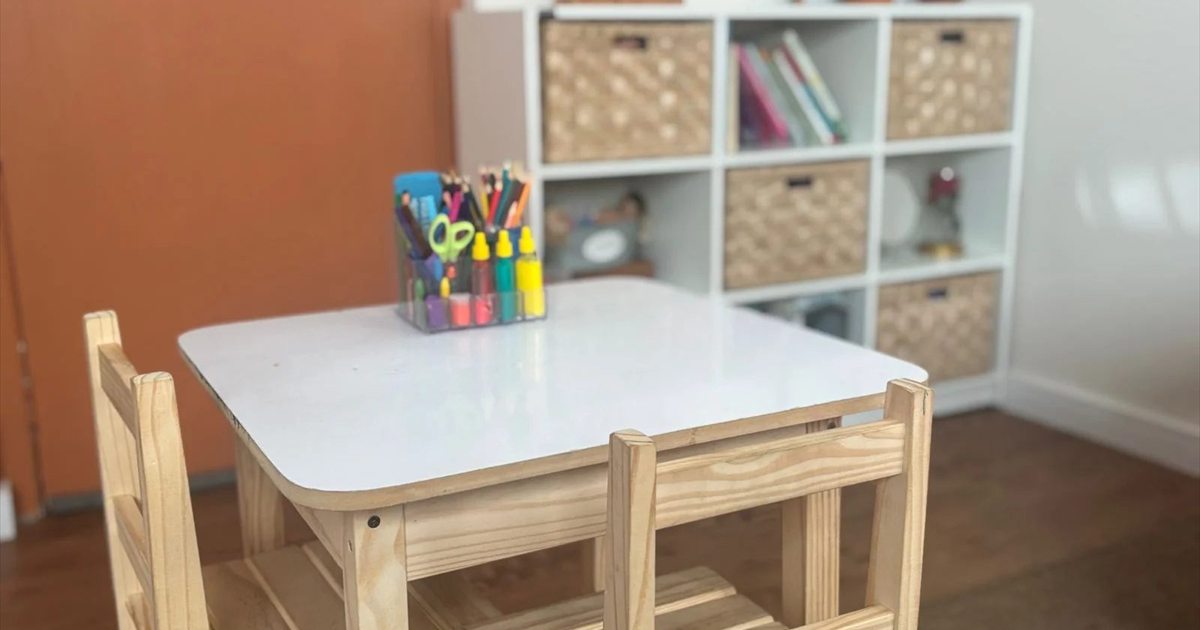Mesa de atividades infantil com lápis de cor e estante de livros